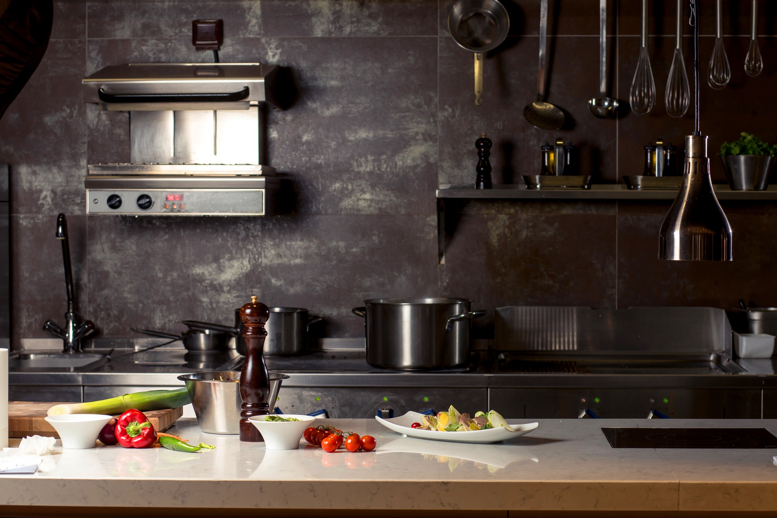 Variety of utensils on counter in commercial kitchen.